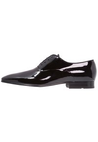 Chaussure de ville en cuir verni noir avec un bout pointu, un système de laçage minimal et un design élégant ; elle est dotée d'un petit talon blocs.