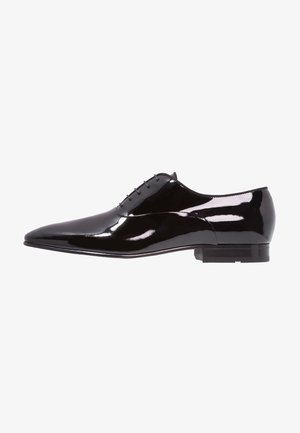 Chaussure de ville en cuir verni noir avec un bout pointu, un système de laçage minimal et un design élégant ; elle est dotée d'un petit talon blocs.