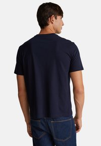 Námořnická modrá bavlněná tričko s krátkým rukávem a kulatým výstřihem, s hladkou texturou a volným střihem, nošeno s modrými džíny.