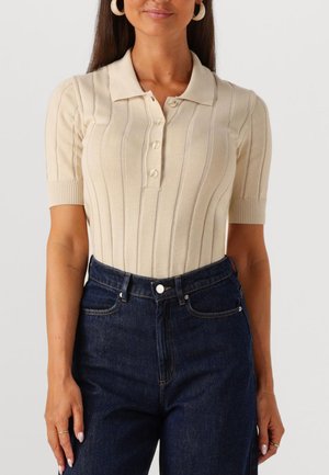 Beige ribbet strikket polo med krave, der har korte ærmer og fem knapper. Sammen med højtaljede mørke denim jeans.