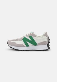 Chaussure de sport avec une tige en daim gris et cuir blanc, des accents en daim vert, une semelle intermédiaire blanche épaisse et une semelle extérieure en caoutchouc noir.