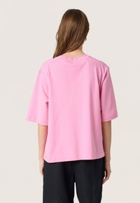 Camiseta de algodón rosa con mangas cortas, corte relajado y escote redondo. Presenta un pequeño logo en relieve en la parte de atrás.