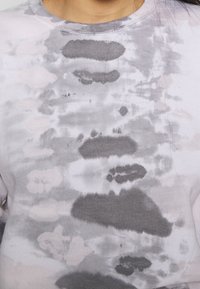 Bavlněná mikina s kombinovaným šedým a světle růžovým tie-dye vzorem, s kulatým výstřihem a jemnou texturovanou tkaninou.