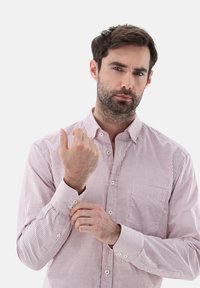 Camicia a righe rossa e bianca con colletto, maniche lunghe e taschino sul petto; tessuto morbido con polsini abbottonati e dettagli.