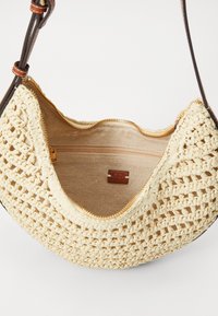 Woven beige handbag with a zip closure, featuring a smooth inner lining and a brown leather strap with a small logo tag.
