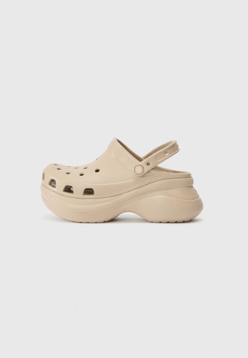 Sabot beige à enfiler avec des trous de ventilation, une bride de talon ajustable et une semelle plateforme épaisse et profilée, présenté en vue latérale sur fond blanc.