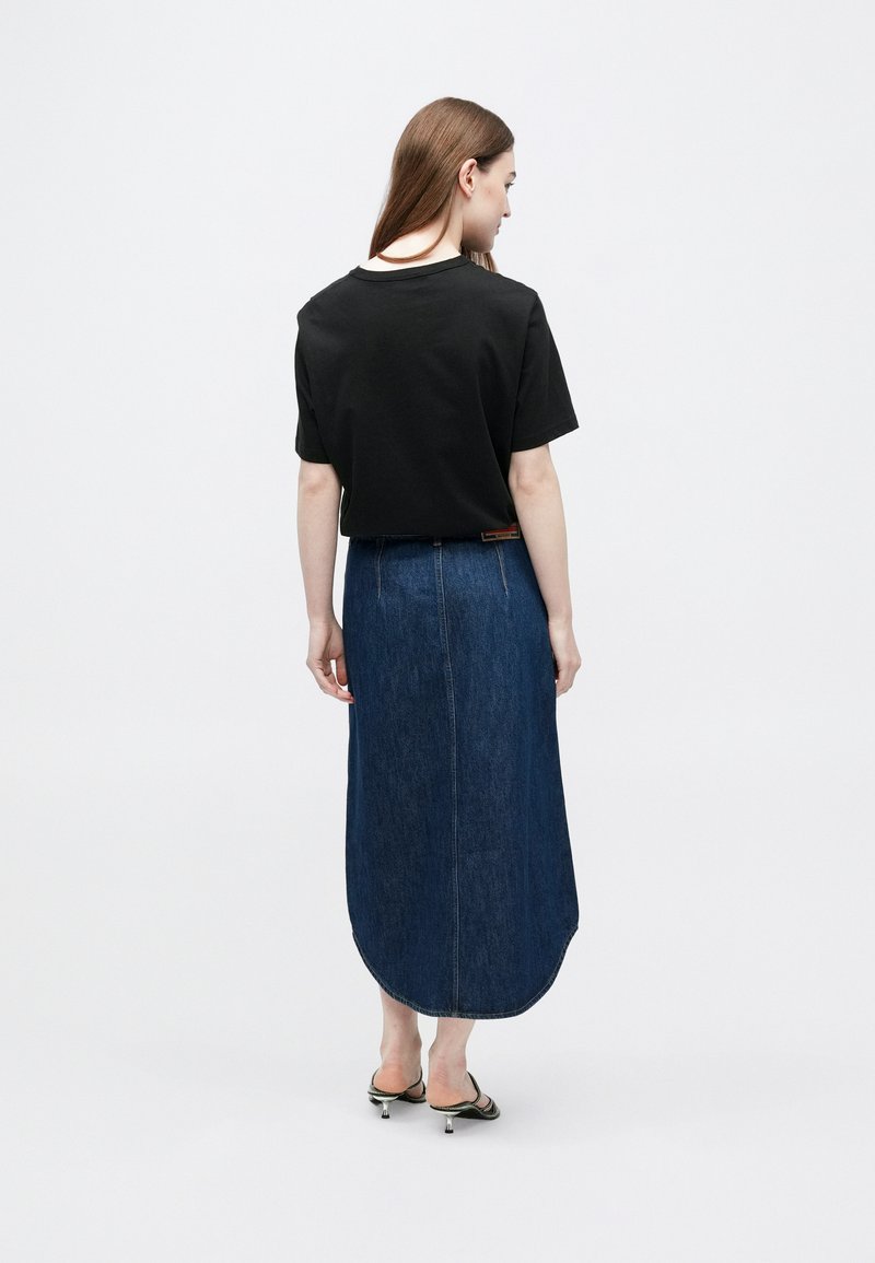 Black cotton t-shirt with short sleeves, paired with a long dark blue denim skirt featuring a curved hem and subtle stitching detail.