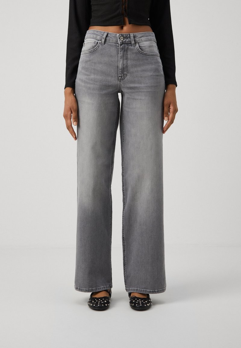 Jean gris à jambes larges en denim, avec un lavage délavé, un design classique à cinq poches, et une fermeture standard à bouton à la taille.