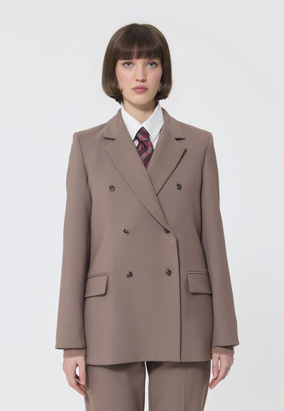 Brauner Doppelreiher-Blazer mit zwei Vordertaschen, kombiniert mit einem weißen Hemd und einer karierten Krawatte. Glatte Textur und strukturierte Passform.