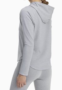 Light grey hoodie with long sleeves and a drawstring hood. Features a soft, smooth texture and a curved hemline. Worn with matching leggings.