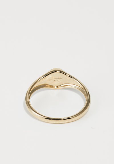 Zelta gredzens ar gludu, izliekta dizaina. Iekšējā joslā ir smalks gravējums. Spīdīga apdare bez redzamām akmeņiem vai dekoriem.