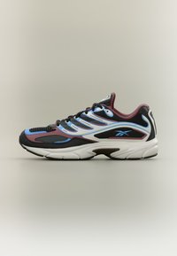 Μαύρο, βουργουνδί και μπλε αθλητικό παπούτσι με λευκή σόλα και λογότυπο Reebok στο πλάι, εμφανιζόμενο σε ουδέτερο φόντο.