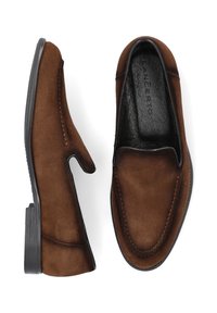 Brązowe zamszowe mokasyny z gładką czarną skórzaną wkładką, okrągłym noskiem i minimalistycznymi detalami szycia. Płaska gumowa podeszwa.