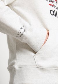 Felpa grigia chiaro con polsini e orlo a costine, dotata di tasca sul davanti e di un logo sulla manica. Morbida al tatto e dal design casual.
