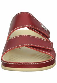 Red leather sandal with two adjustable straps, white stitching, and a textured beige insole. Open-toe design with a flat sole.