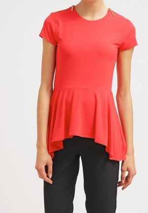 Rød peplumtop med korte ærmer, der har guldaccentuer på skuldersømmene og en flydende, asymmetrisk kant. Glat stofstruktur.