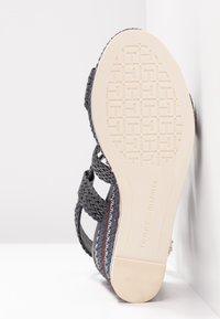 Semelle d'une sandale compensée tissée multicolore avec un dessous beige texturé et le logo "Tommy Hilfiger" embossé près du talon.
