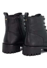 Black leather ankle boots with a textured finish, lace-up front, side zipper, and chunky rubber soles with deep treads. Gold logo accent.