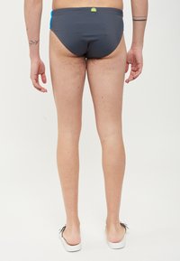 Grijze zwembroek met blauwe accenten, met een lage taille en een elastische tailleband. Gladde textuur, minimale bedekking en logo-detail op de achterkant.