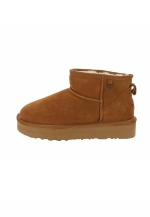 Bruine nubuck enkellaarzen met een ronde neus, schapenvachtvoering en een kleine decoratieve zijknop. Platte rubberen zool met een gestructureerde grip.