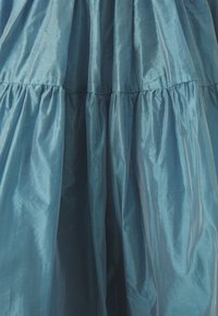 Abito maxi satinato color acquamarina con tiers arricciati, caratterizzato da una texture liscia e una morbida lucentezza. Il tessuto si drappeggia elegantemente, enfatizzando il volume.