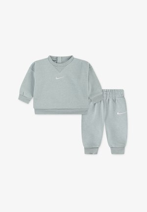 Sweat-shirt Nike gris clair avec col en V et manches longues, assorti à un pantalon de jogging avec poignets élastiques et détails logo.