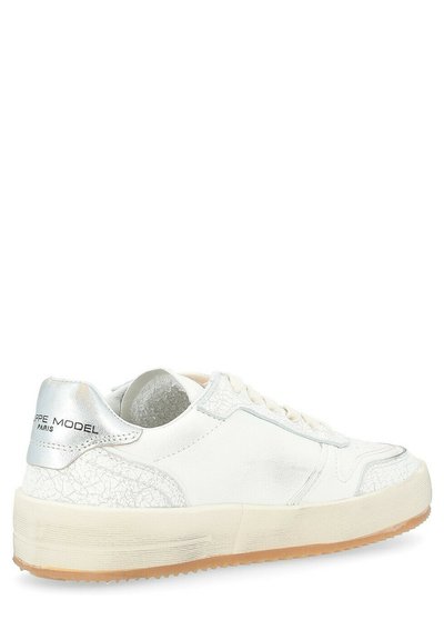 Witte leren sneaker met een gestructureerde zilveren accent op de hak, platte gumzool en subtiele stikdetails aan de zijkanten.