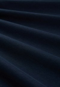 Marineblaue Stoff mit glatter Textur, in sanften Falten präsentiert, zeigt eine gleichmäßige, einheitliche Farbe ohne Muster oder Verzierungen.