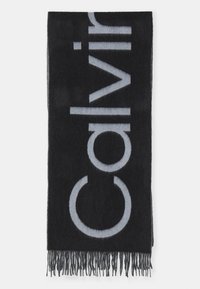 Juodas šalikas su dideliu pilku tekstu, minkšta tekstūra ir plonu kraštu. Medžiaga atrodo kaip vilna arba panaši tekstilė.