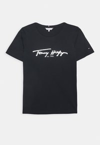 Černé bavlněné tričko s krátkým rukávem. Obsahuje bílé logo "Tommy Hilfiger" a text "est. 1985". Na rukávu se nachází malé logo.