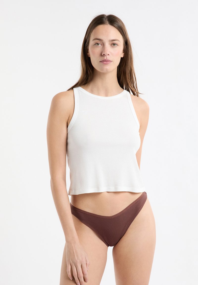 Top corto bianco con scollo rotondo e spalline larghe, abbinato a biancheria intima marrone a coste. Design semplice e texture liscia.