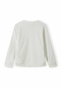 Haut à manches longues blanc avec un motif étoilé texturé, fabriqué en tissu doux. Encolure arrondie et poignets ajustés aux manches et à l'ourlet.