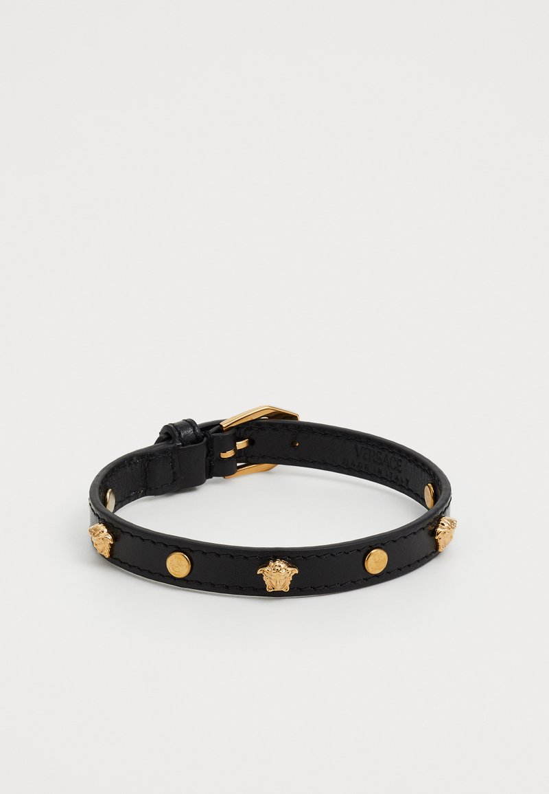 Musta nahkaranneke, jossa on kultainen solki ja vuorottelevat kultaiset Medusa-pääkset ja pyöreät niitit, merkitty Versace, valmistettu Italiassa.