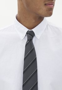 Pilkas ir juodas dryžuotas kaklaraištis, pagamintas iš struktūrinio audinio, dėvimas ant balto apykaklės marškinio. Kaklaraištis turi siauras įstrižaines.