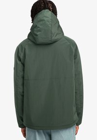 Green hooded jacket with a textured fabric, featuring a straight cut and visible seams. Minimal logo detail on the sleeve.