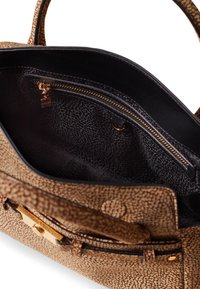 Sac à main en cuir marron texturé avec un intérieur noir, comprenant une poche zippée et des accents en matériel doré. La conception présente une forme structurée.