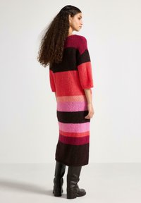 Strikket kjole med vertikale striber i nuancer af rød, pink og brun. Lange ærmer og en midilengde med en blød tekstur.