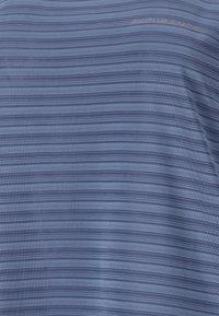 Blauw gestreepte stof met verschillende tinten blauw, een duidelijk gladde textuur en een lichte merknaam in de bovenlinkerhoek.