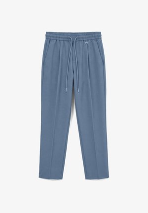 Blaue, zulaufende Sweatpants mit elastischem Bund, Kordelzug, Seitentaschen und einem kleinen Metallring neben der rechten Tasche.