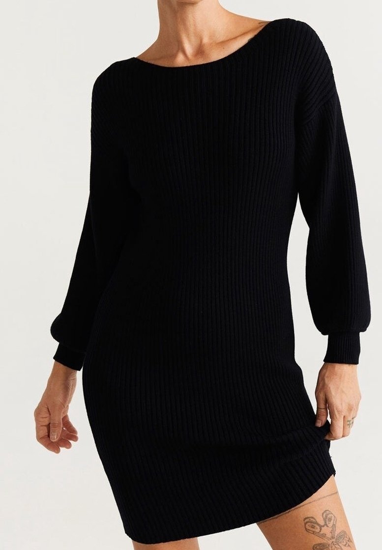 Robe noire en tricot à côtes avec encolure bateau, manches longues bouffantes et silhouette cintrée. Texture douce, ourlet à mi-genoux.
