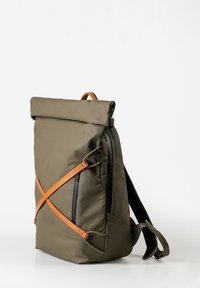 Zaino a sacca verde oliva con dettagli in pelle marrone, progettato con una forma elegante, cerniere e spallacci regolabili per una vestibilità ergonomica.