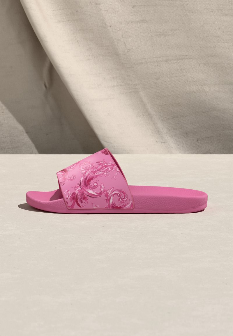 Sandalia de goma rosa con una correa ancha que presenta un patrón floral. Plantilla texturizada y superficie exterior lisa. Diseño ligero.