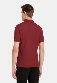 Bordowa koszulka polo wykonana z gładkiego materiału, z krótkimi rękawami i klasycznym kołnierzykiem, z czystym widokiem z tyłu i bez widocznych wzorów.