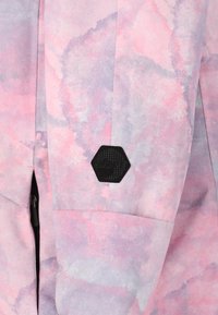 Jacket mit Pastellmuster in verschiedenen Pink- und lila Tönen, ausgestattet mit einem schwarzen sechseckigen Logo-Patch und einem Reißverschlusstaschen-Detail.