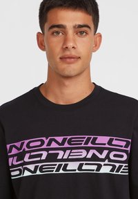 Black cotton t-shirt featuring bold, layered text in purple and pink gradients across the chest. Classic crew neck and short sleeves.