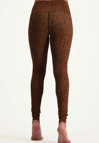 Svart och orange mönstrade leggings med en slät textur, figurnära design och detalj vid ankeln. Justerbart midjeband för komfort.
