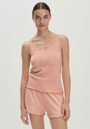 Top a canotta rigata di un delicato rosa chiaro con spalline regolabili e bordi a scallop, abbinata a pantaloni shorts coordinati che presentano una texture e un design simili.