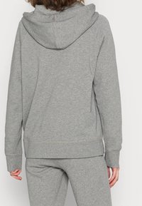 Felpa grigia realizzata in morbido tessuto, con cappuccio regolabile tramite coulisse, polsini e orlo a coste, e dettagli di cucitura in vista.