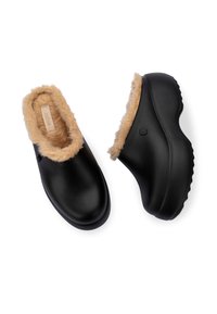 Czarne chodaki z miękkim, jasno-beżowym sztucznym futrem, zaokrąglonym kształtem, teksturowanymi podeszwami i gładkim wykończeniem. Posiadają dyskretną logo marki z boku.