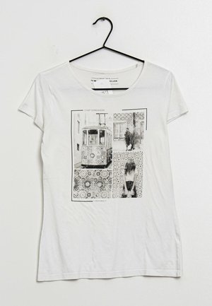Camiseta blanca con cuello redondo que presenta un collage gráfico en blanco y negro de un tranvía y fondos con patrones. Tejido suave, mangas cortas.